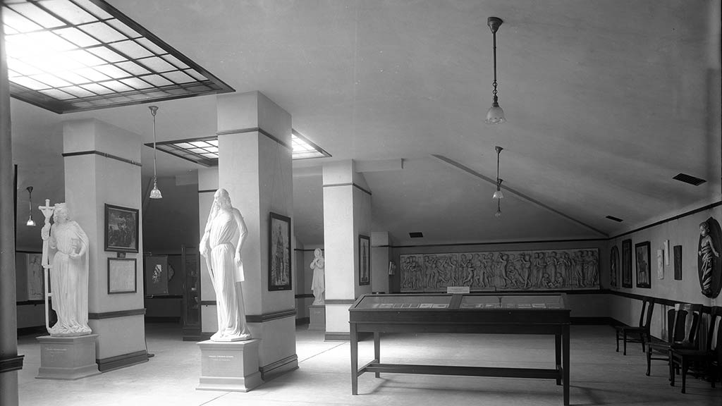 light streaming down on two statues in a historical gallery photo