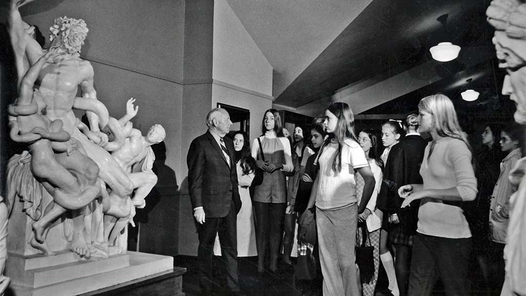 1960's era docent gives a tour to colleges students