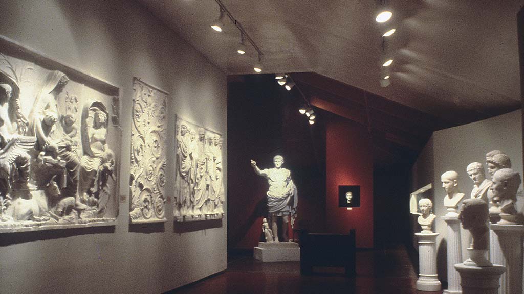 red and white gallery with statues and relief panels