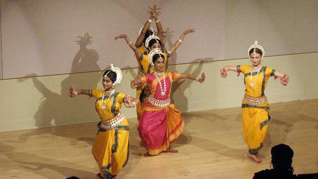 expressive Indian dancers in pink and yellow costumes