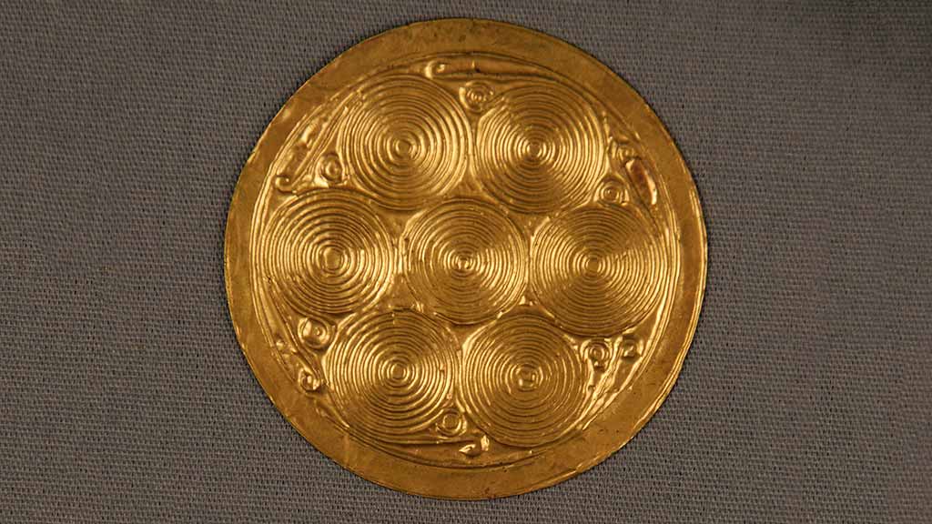 small gold disc with 7-circle embossed design