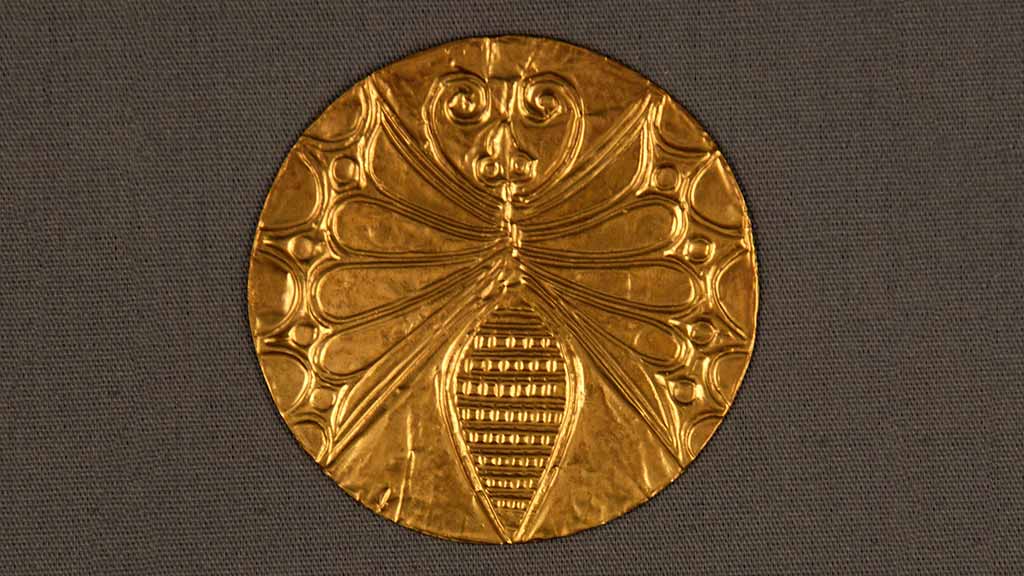 small gold disc with embossed spider design