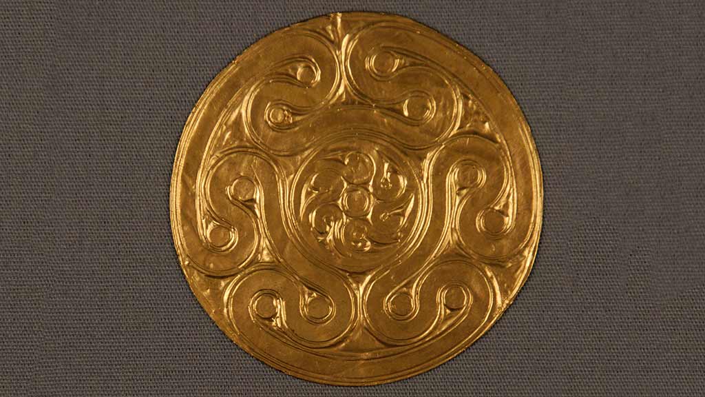small gold disc with embossed geometric curly design