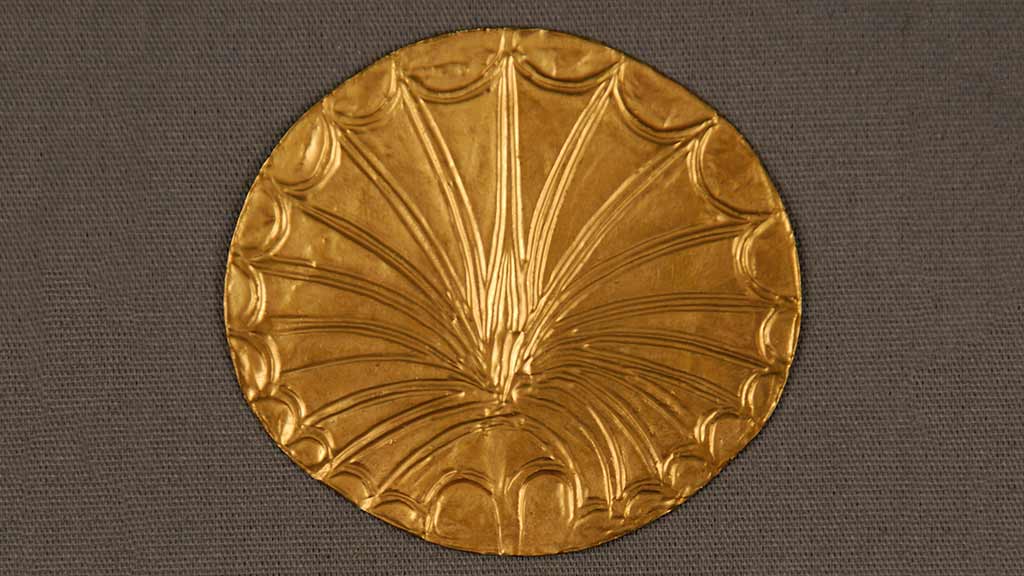 small gold disc with embossed flower design