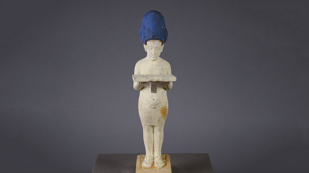 slender figure wearing a brilliant blue tall hat and holding a flat object