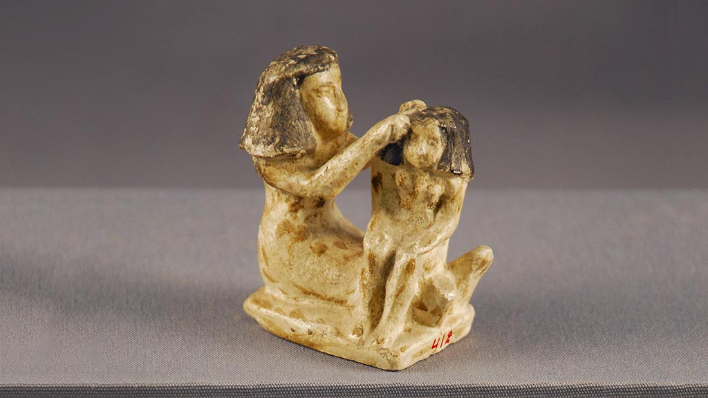 figurine of a seated woman fixing a child's hair