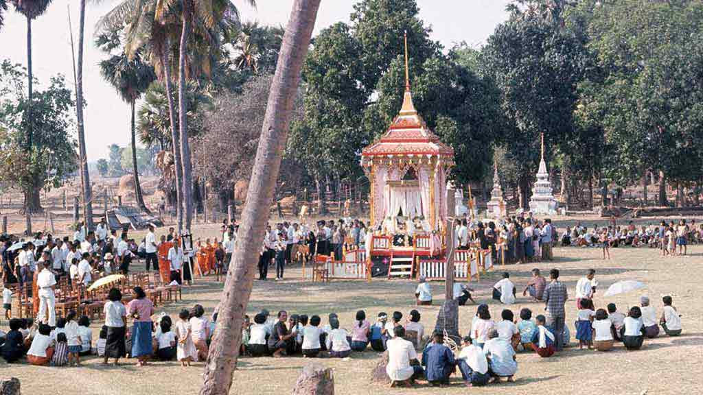 people gather around a structure at an outdoor funeral