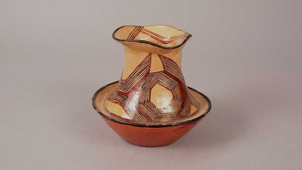 white ceramic vessel with red and black geometic designs