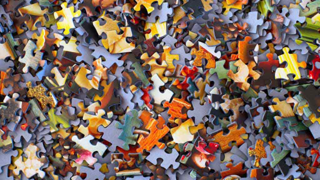 collage of multi-colored jigsaw puzzle pieces in pile