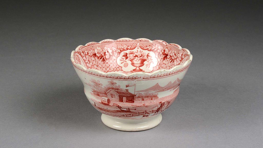Small cream and red ceramic cup with log cabin imagery and flower detail