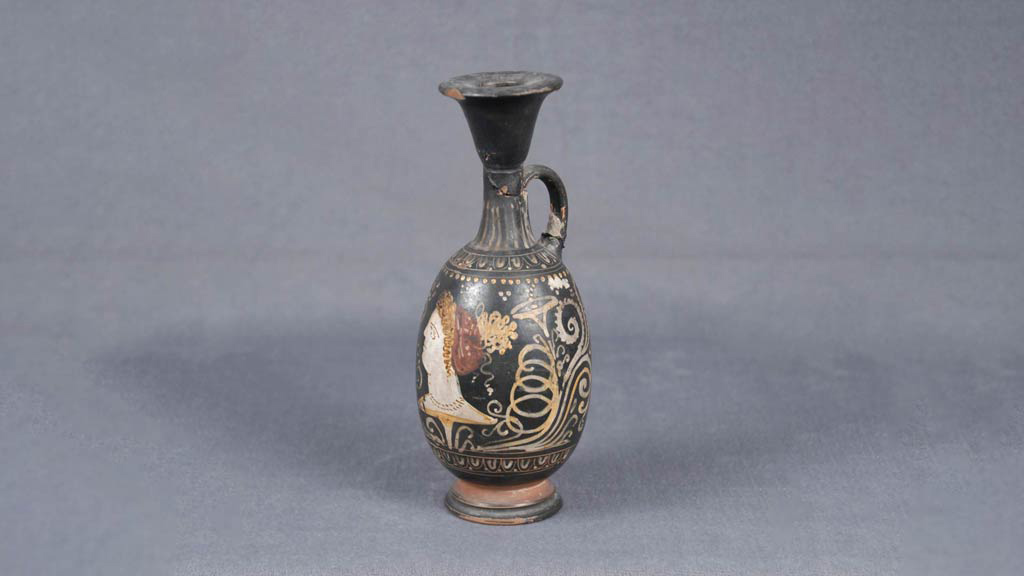 three-quarter view of black oil bottle painted with gold patterns and decals