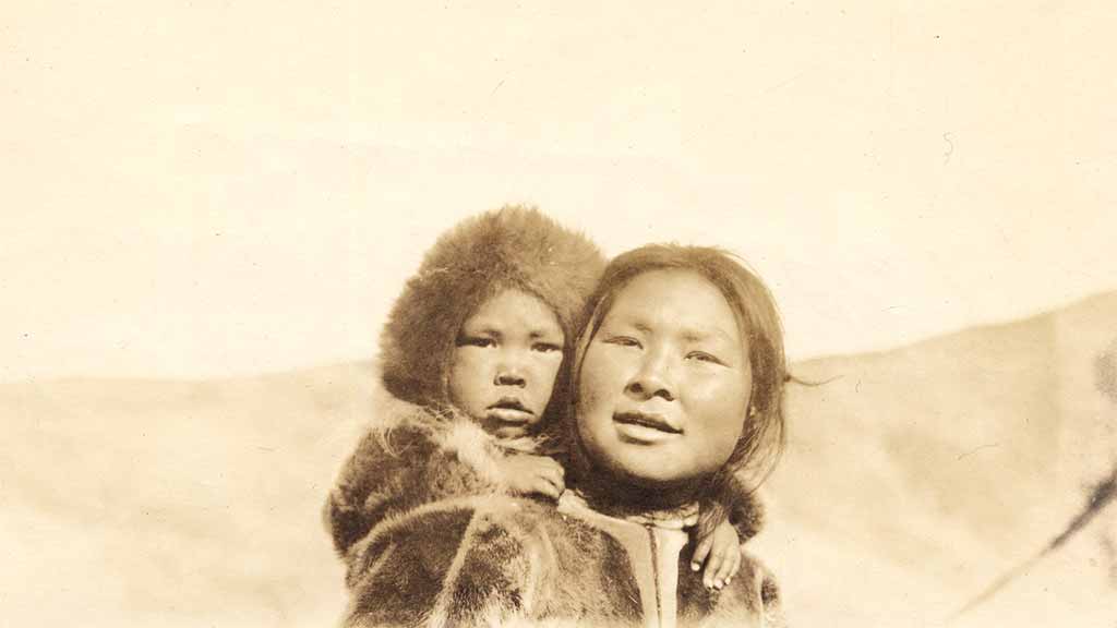 Two smiling inuit, including one small child