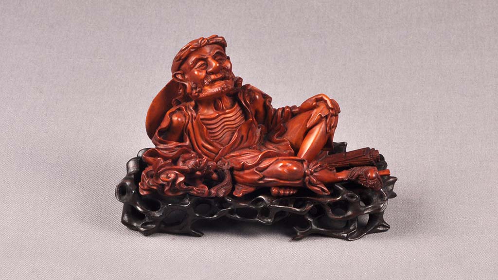 carved brush rest in the shape of an old reclining man