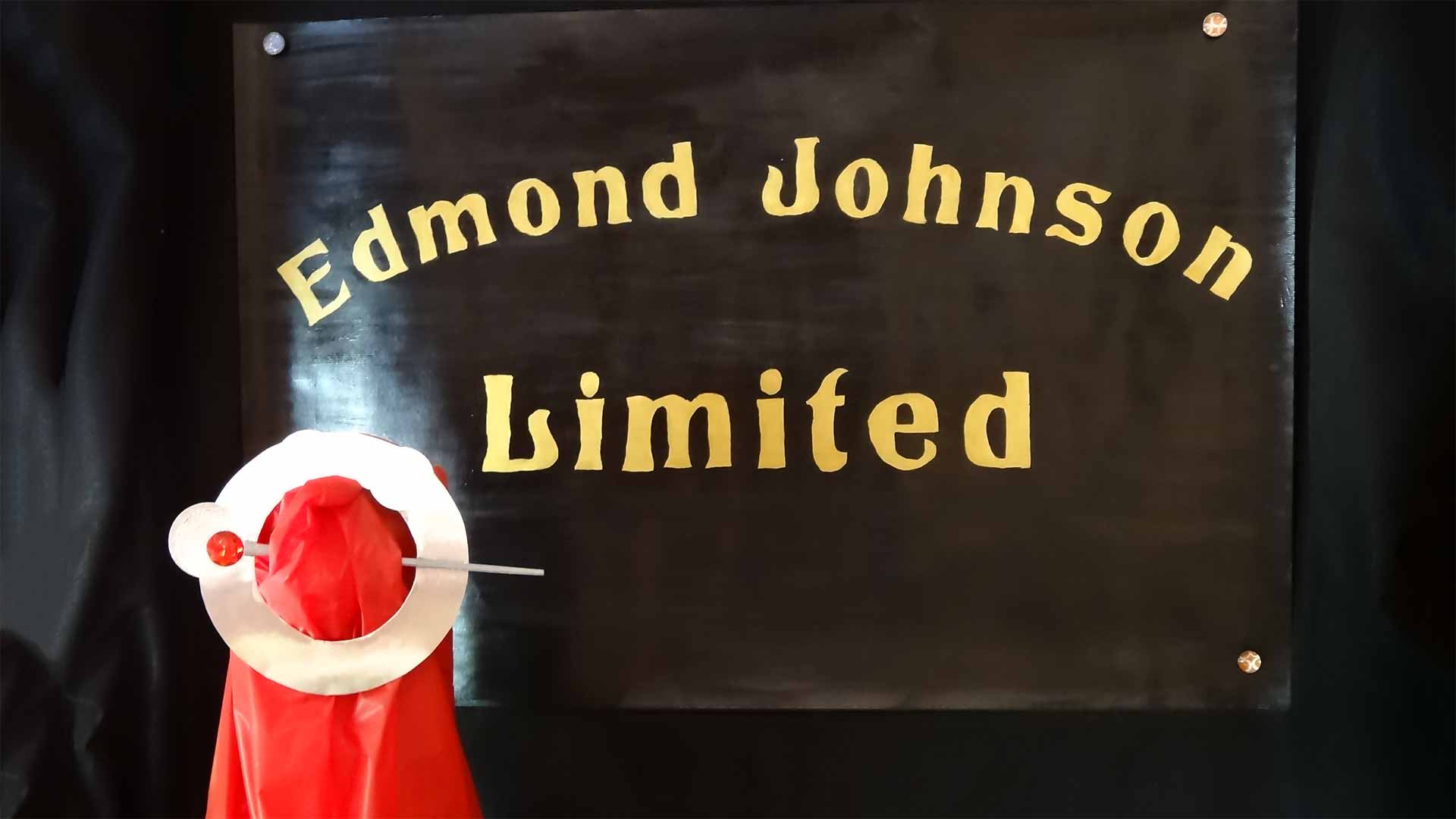 sign reading "edmond johnson limited" with a piece of fabric and pin brooch