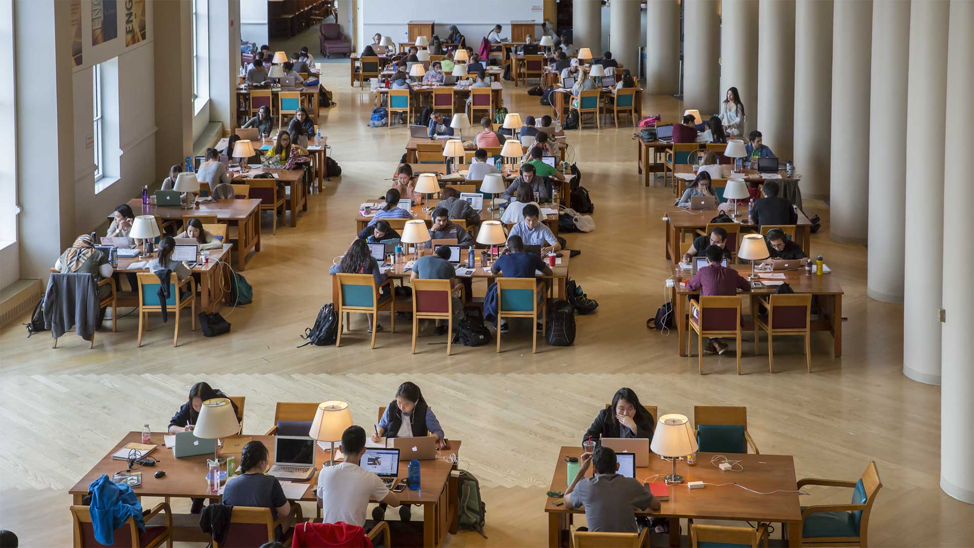 A large number of students studies at a number of tables in Grainger Library