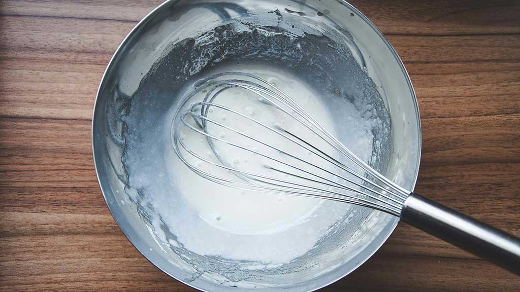 bowl of cooking batter with a whisk in center