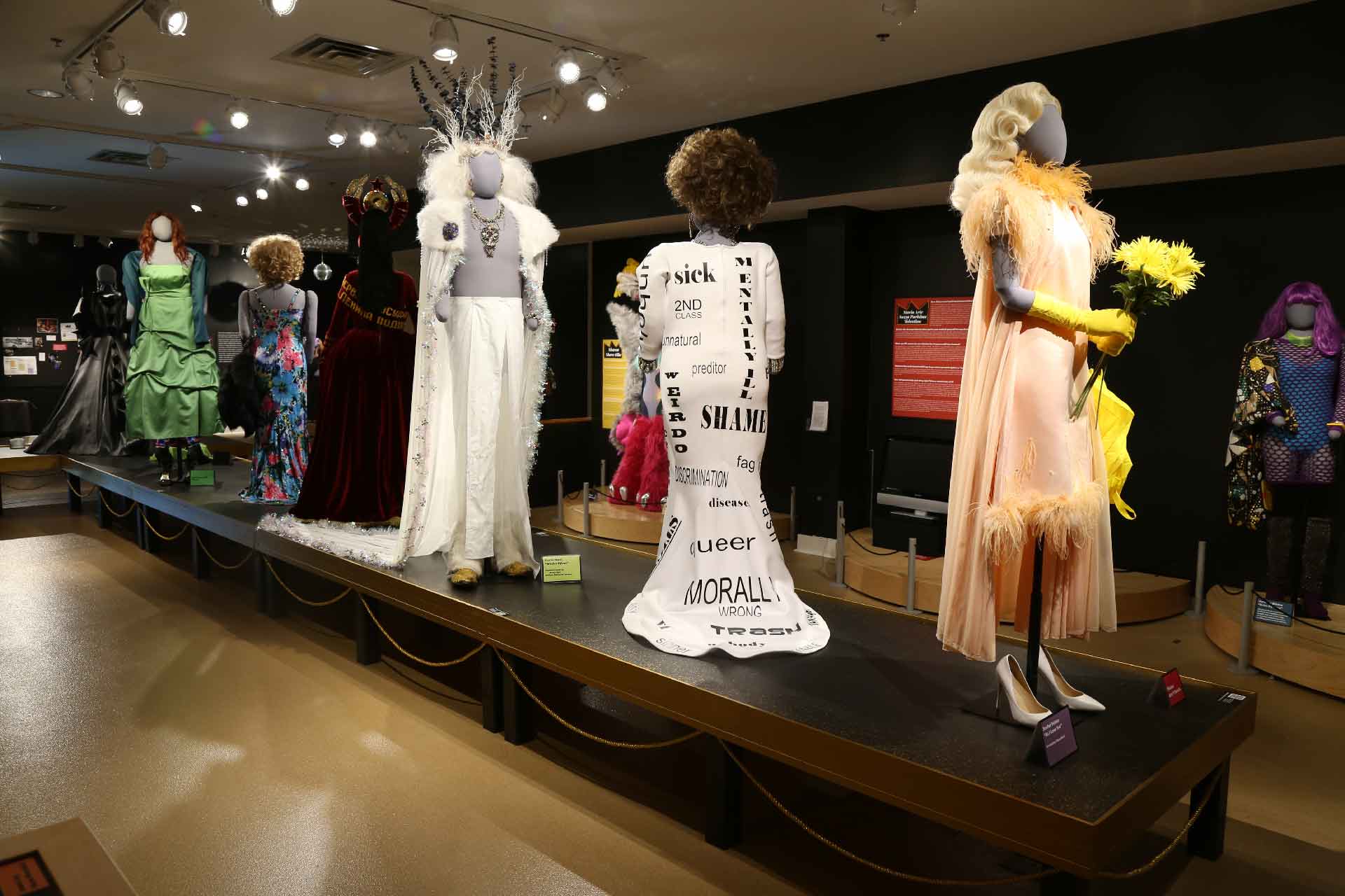 back view of exhibit featuring mannequin in pink drag costume in the front