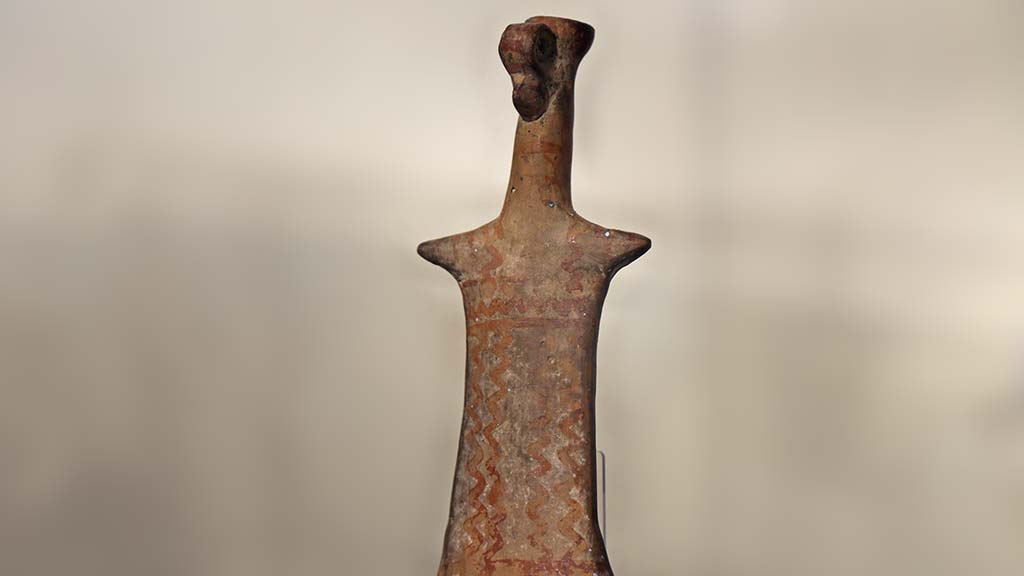 heavily stylized terracotta figure with a long neck and very short arms