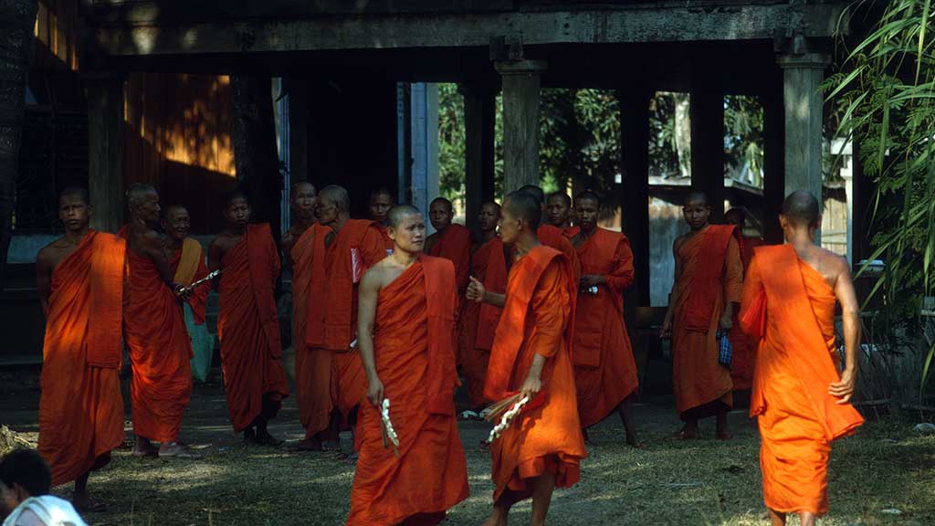monks in orange robes convene outside of a temple