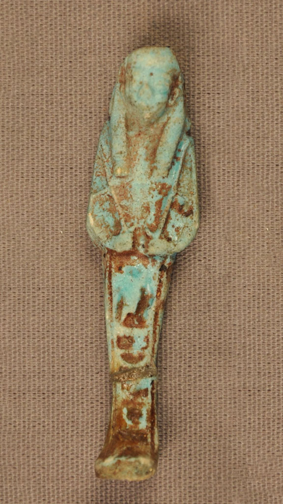 green stone carving of a mummified human with brown substance