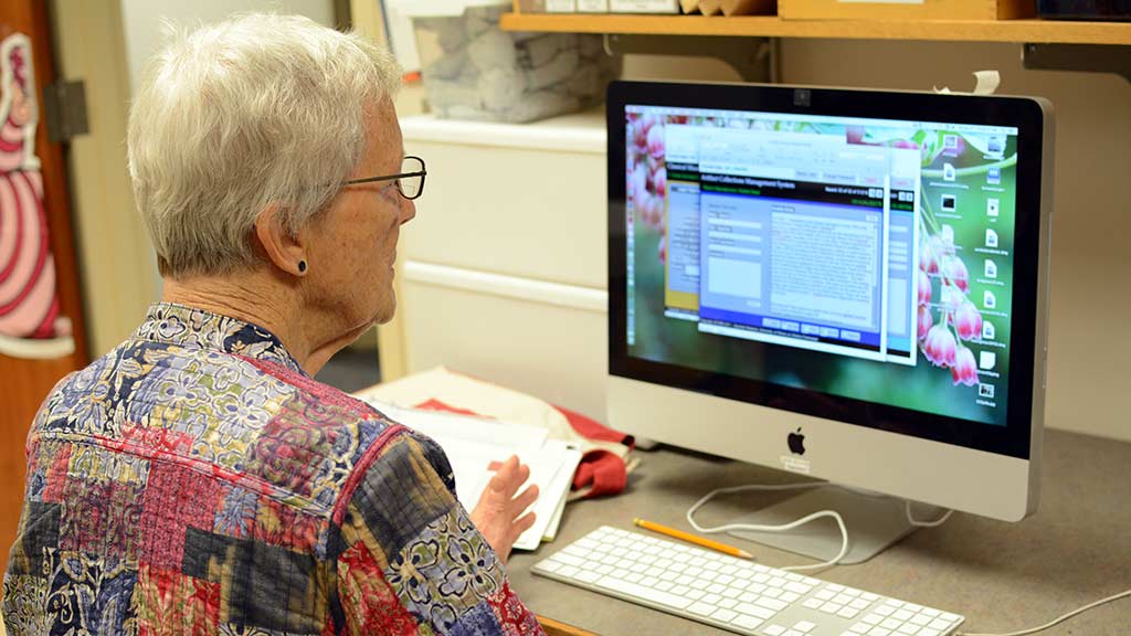 volunteer researches objects in a collection database on a computer