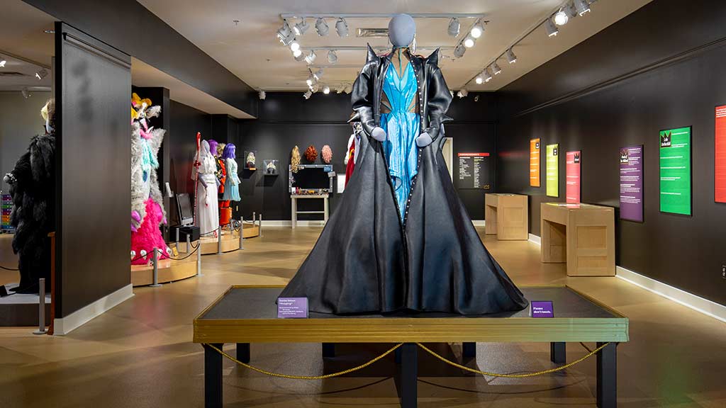 exhibit overview featuring an elaborate costume gown in black and teal