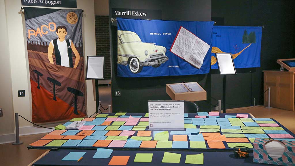 table of post-it notes from an activity in front of an exhibit of fabric quilt panels for Paco and Merrill Eskew