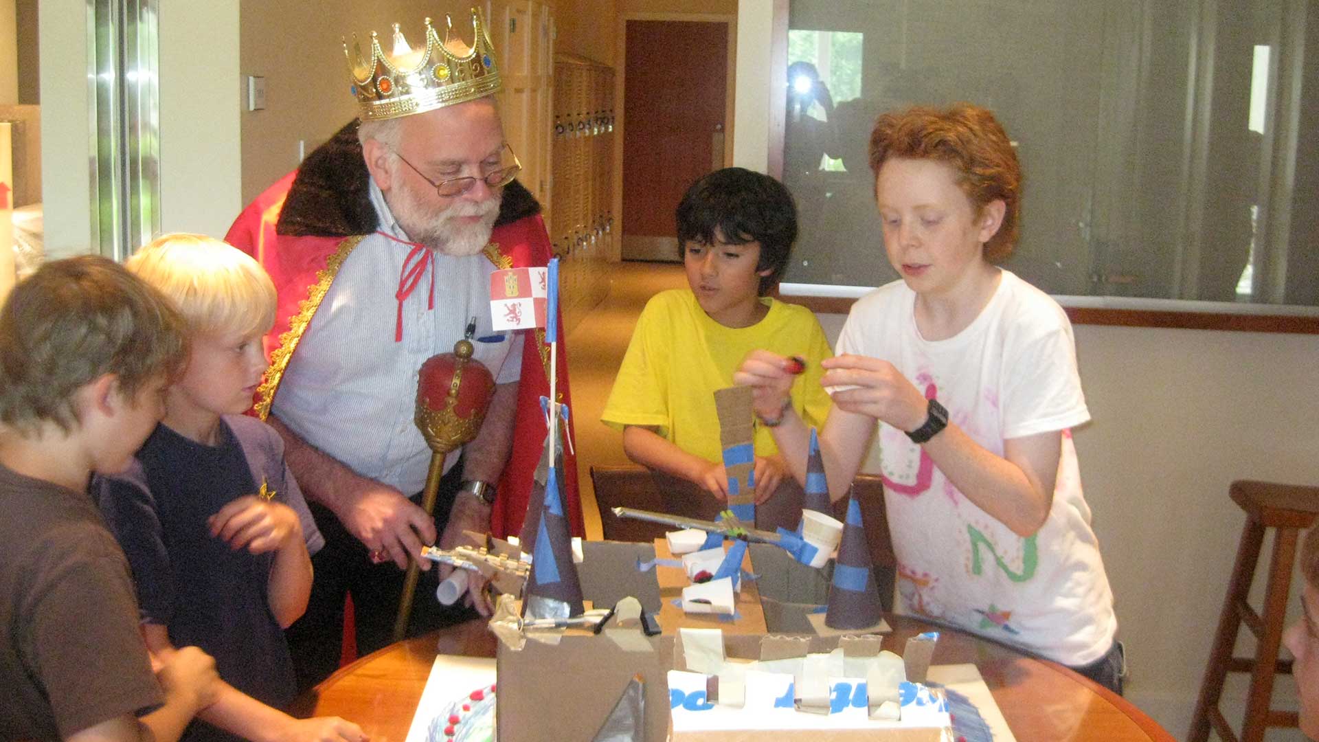 employee dressed as a king examines catapults with kids