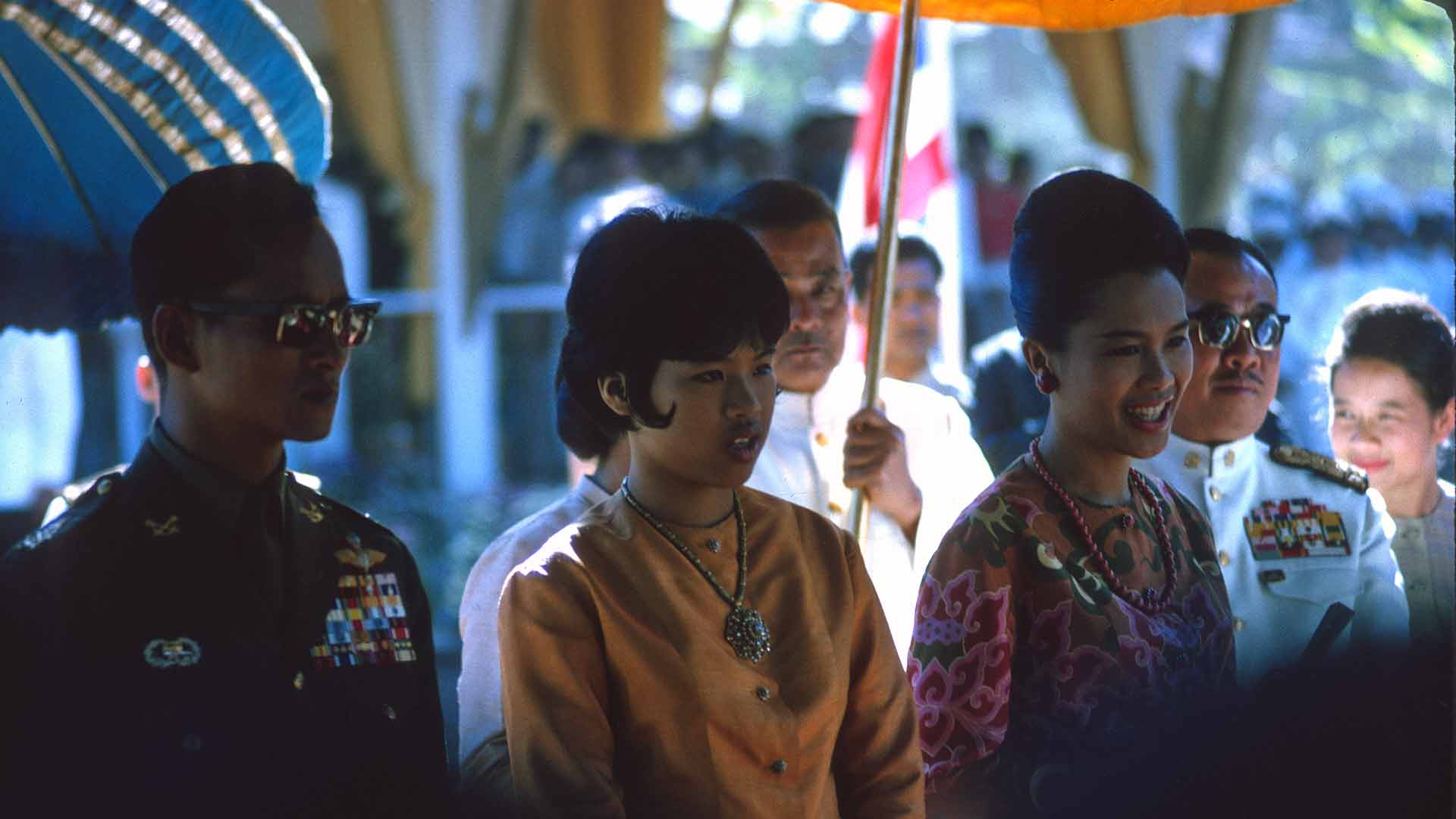 Same two women, smiling, escorted by two military personnel