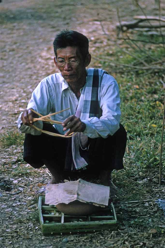 A man sits in front of the clay pot now covered with paper.