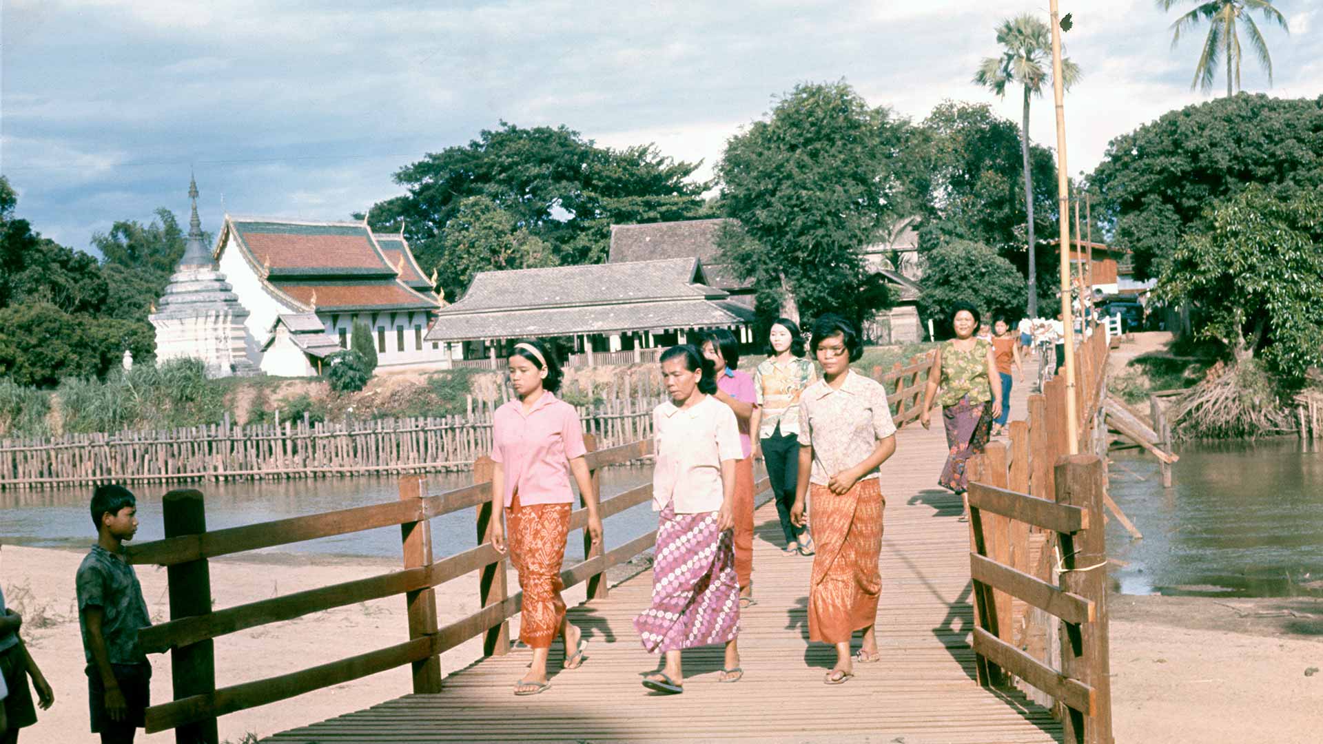 women cross a wooden pedestrian bridge