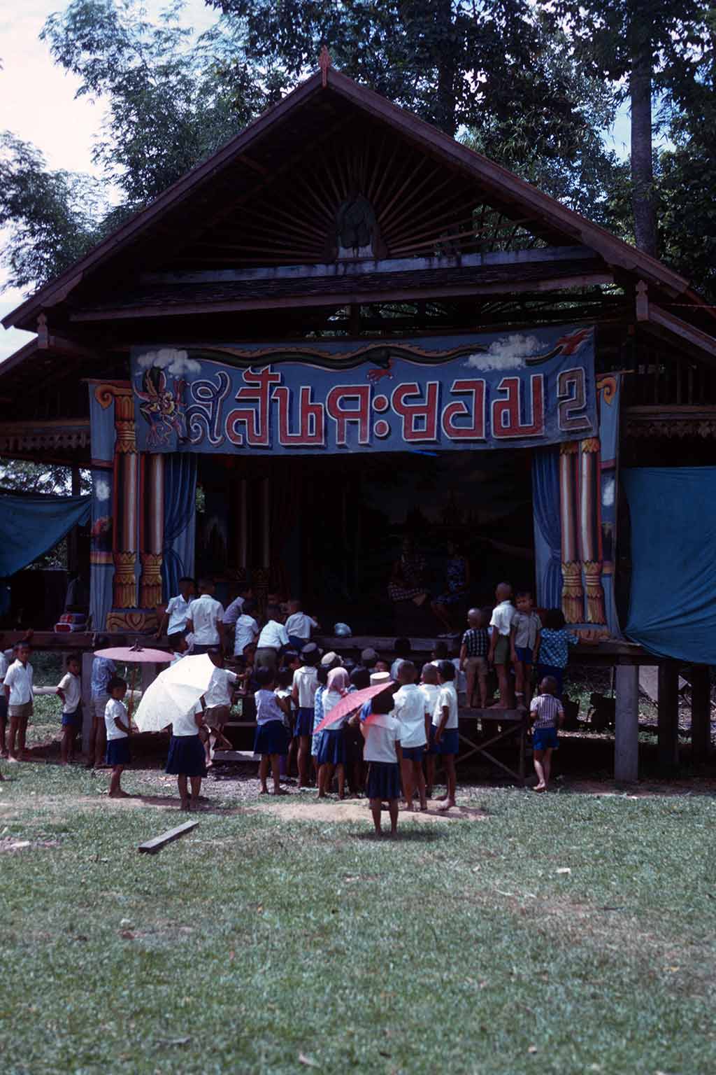 People gather around a large stage in the sun