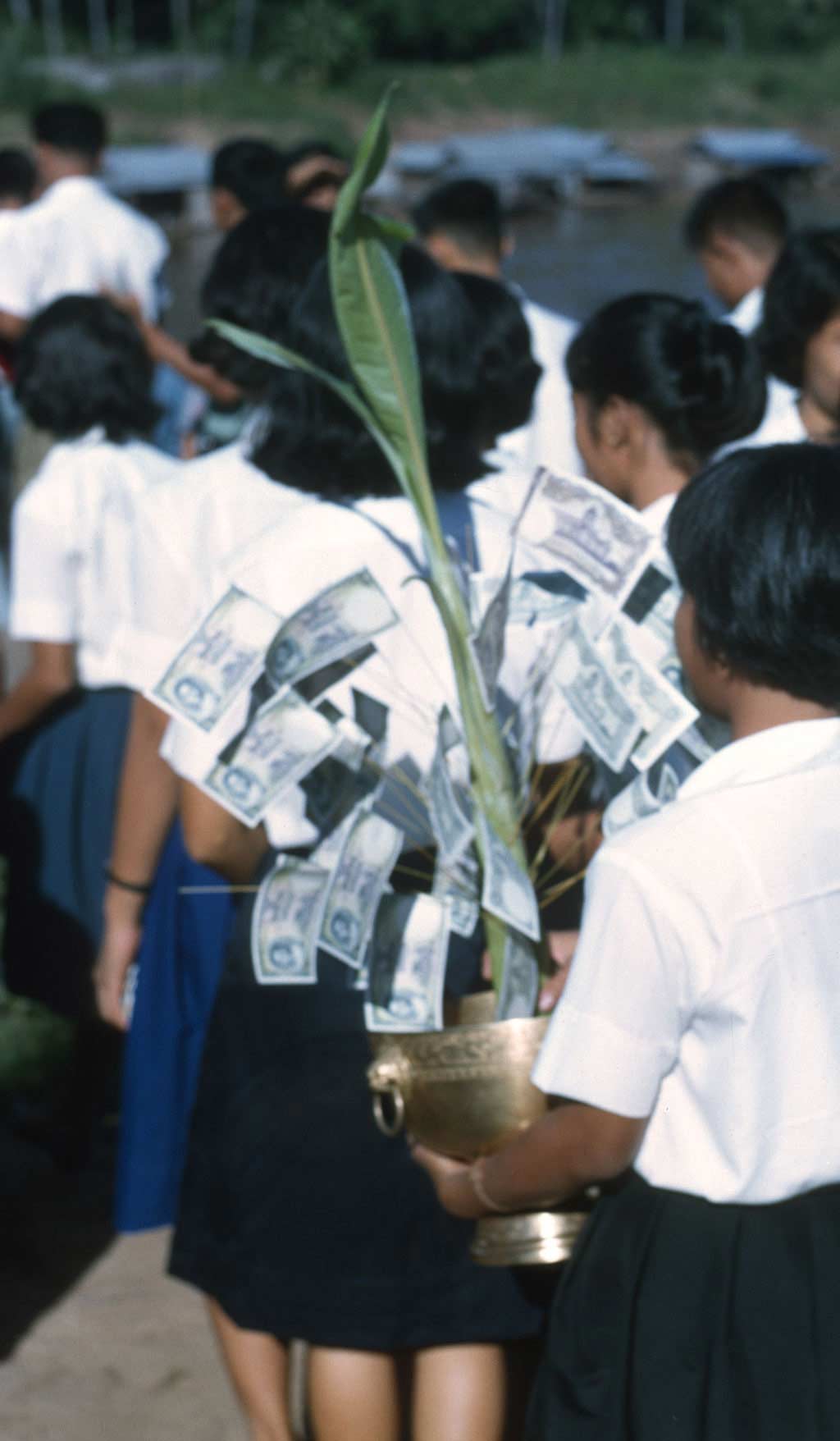 A group of school girls carrying alms in the form of a palm tree to give to the monks.