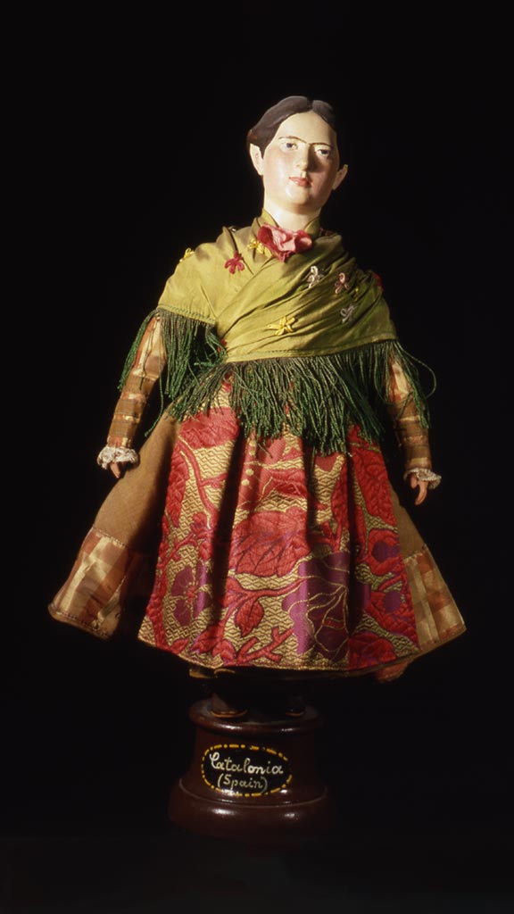 female doll wearing a green top and a red and gold skirt