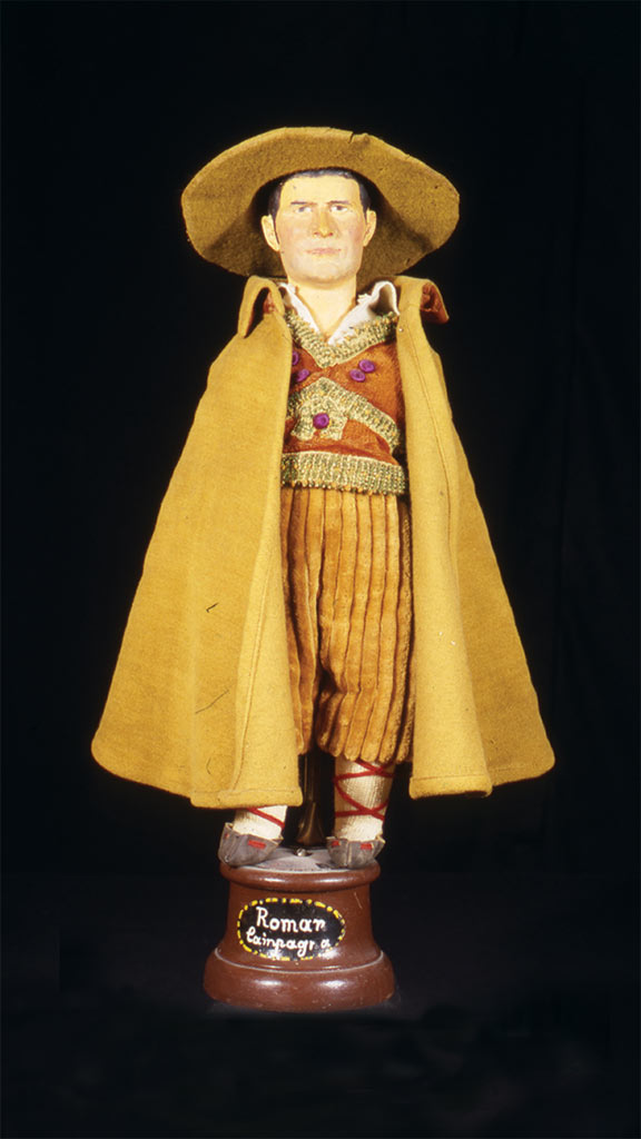 male doll wearing a gold hat and gold clothing with a gold cape