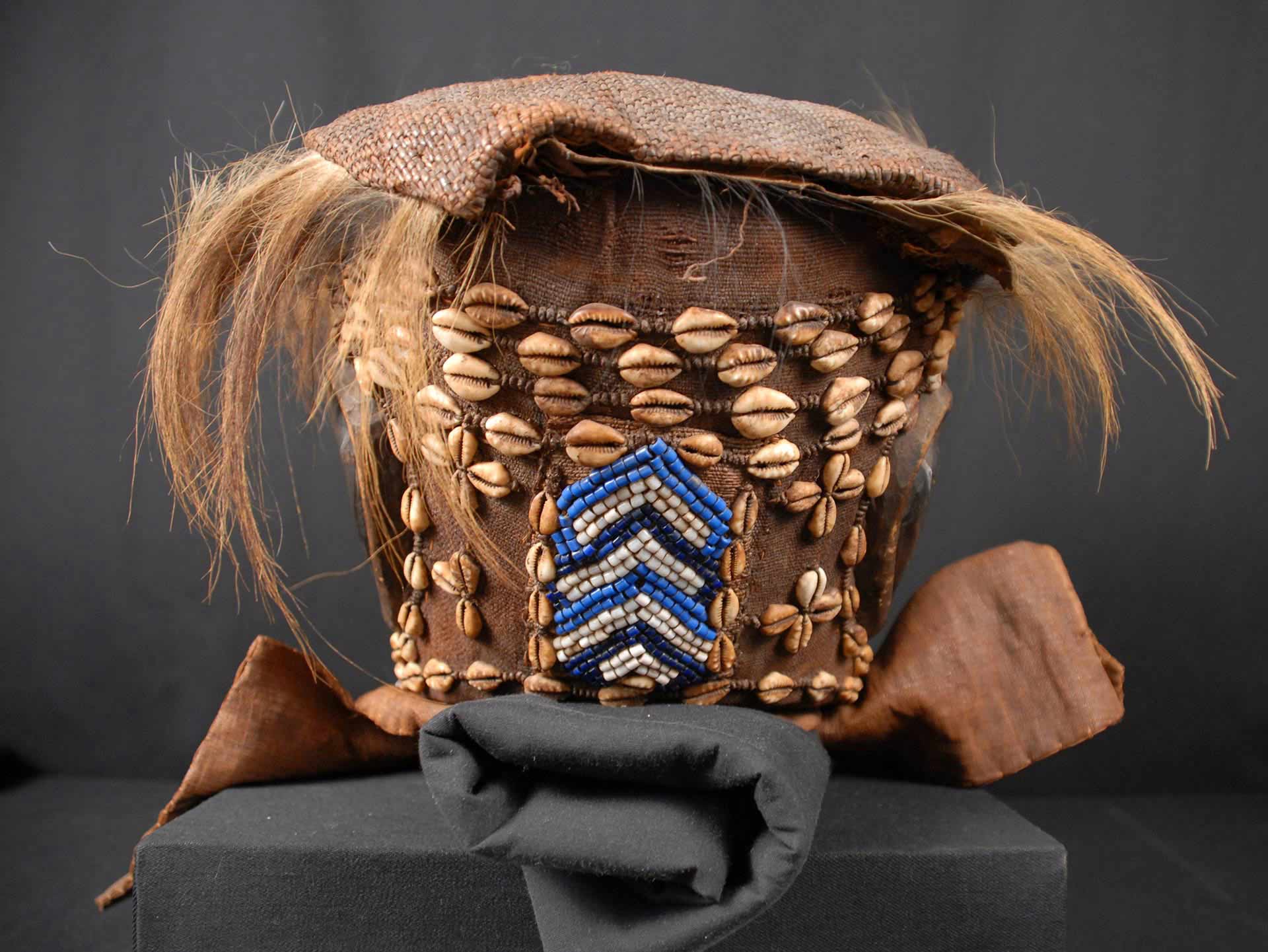 Burlap cloth attached to top of head, hair coming from edges of burlap, colored beads attached