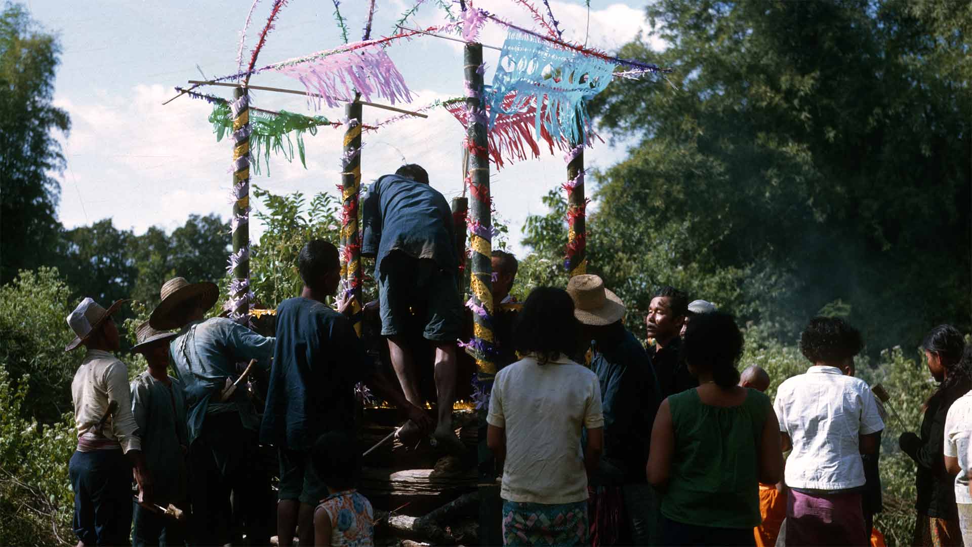 villagers gathered around decorated funeral pyre