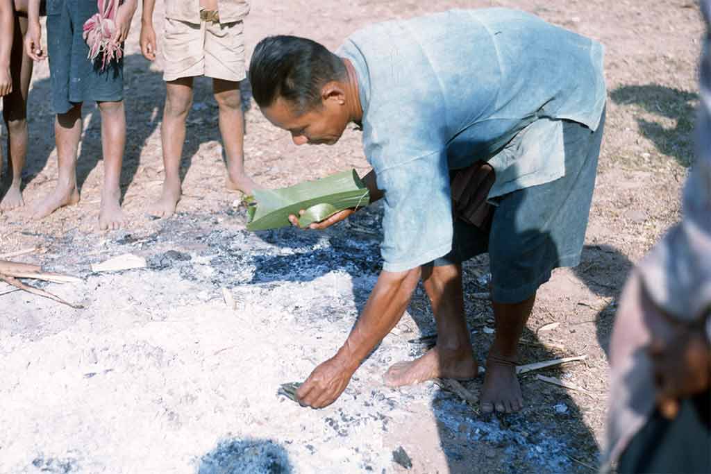 Man sifting through ash collecting bones