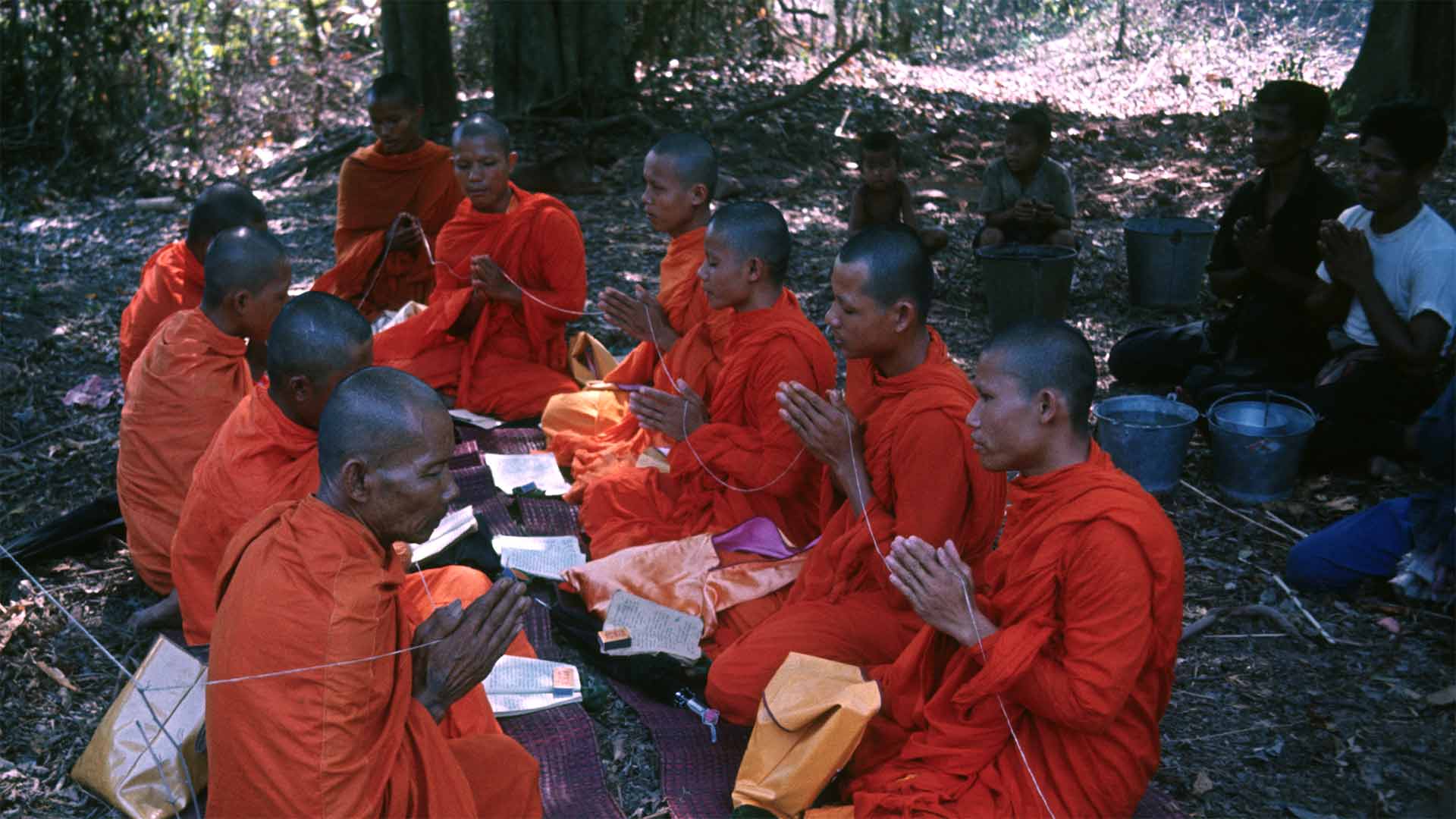 monks praying in clearing, others praying in background