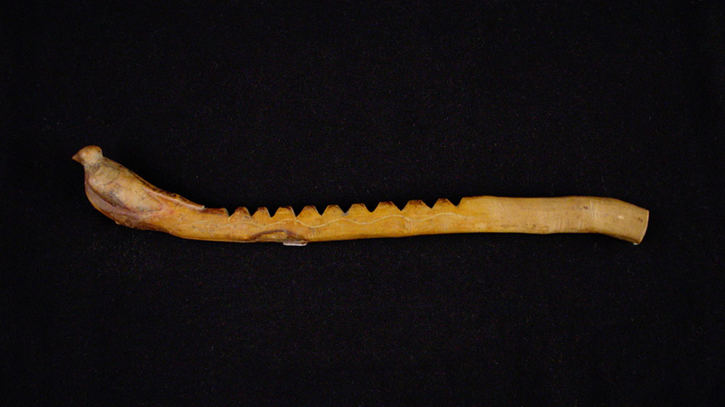 narrow wooden stick with carved notches along one side