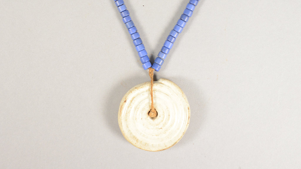 A large wooden pendant on a necklace with beads