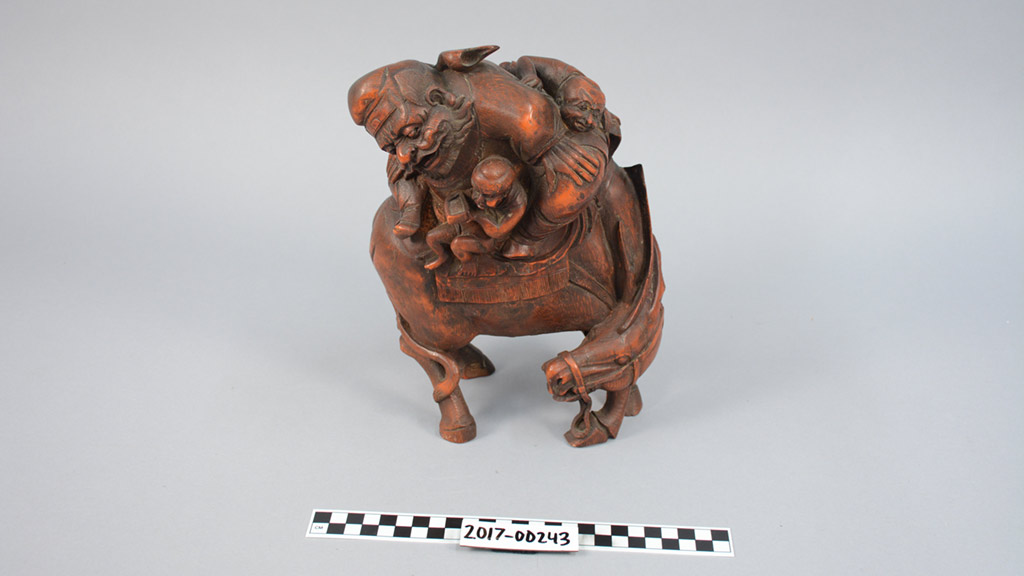 Bamboo carving of a man and two small figures on donkey
