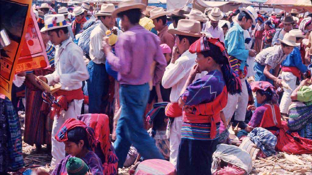 People in colorful clothing walk around a crowded marketplace