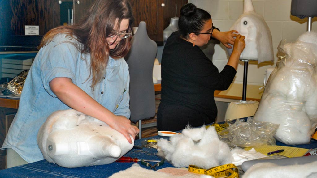 Two students sculpt exhibit mannequin torsos out of styrofoam