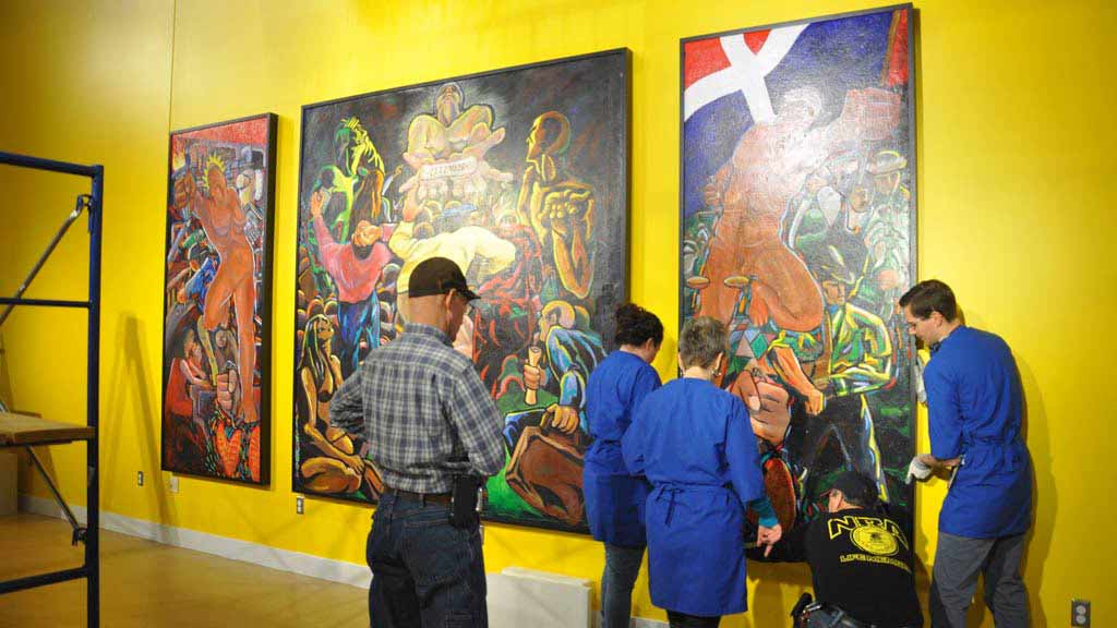 three Spurlock staff members and two Facilities and Services workers installing a third mural panel in the Spurlock Museum