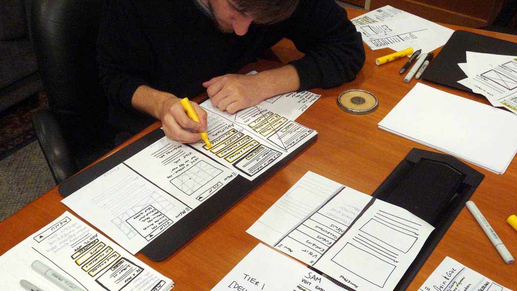 Andy sitting at a table covered with papers highlighting one of the papers