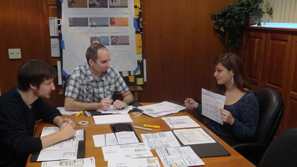 A group of 3 people conversing in the conference room