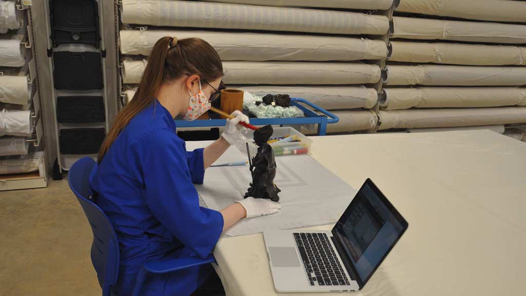 woman cleaning an object with a laptop next to her