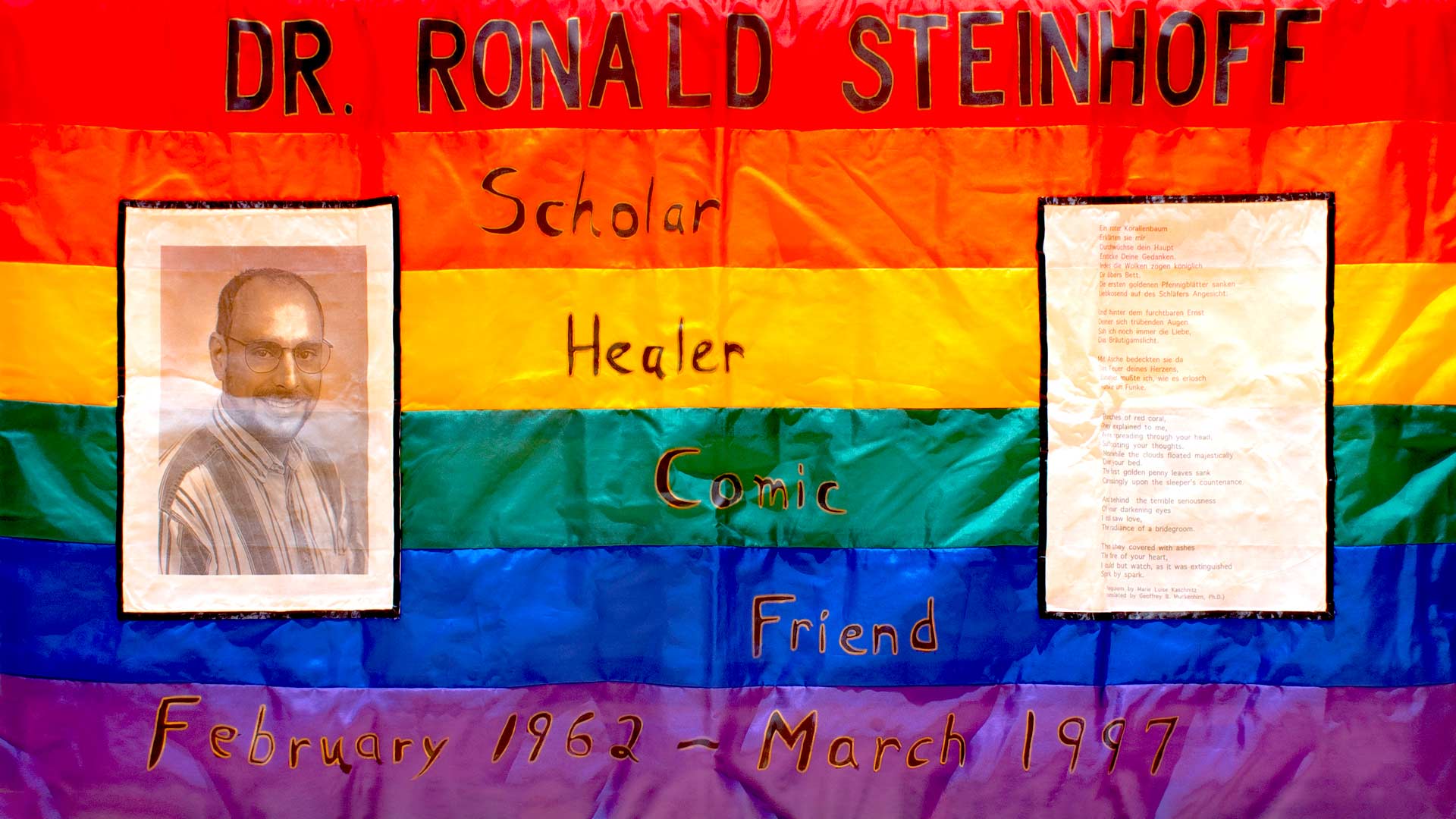 Fabric panel of a rainbow background with a photo of a man and writing