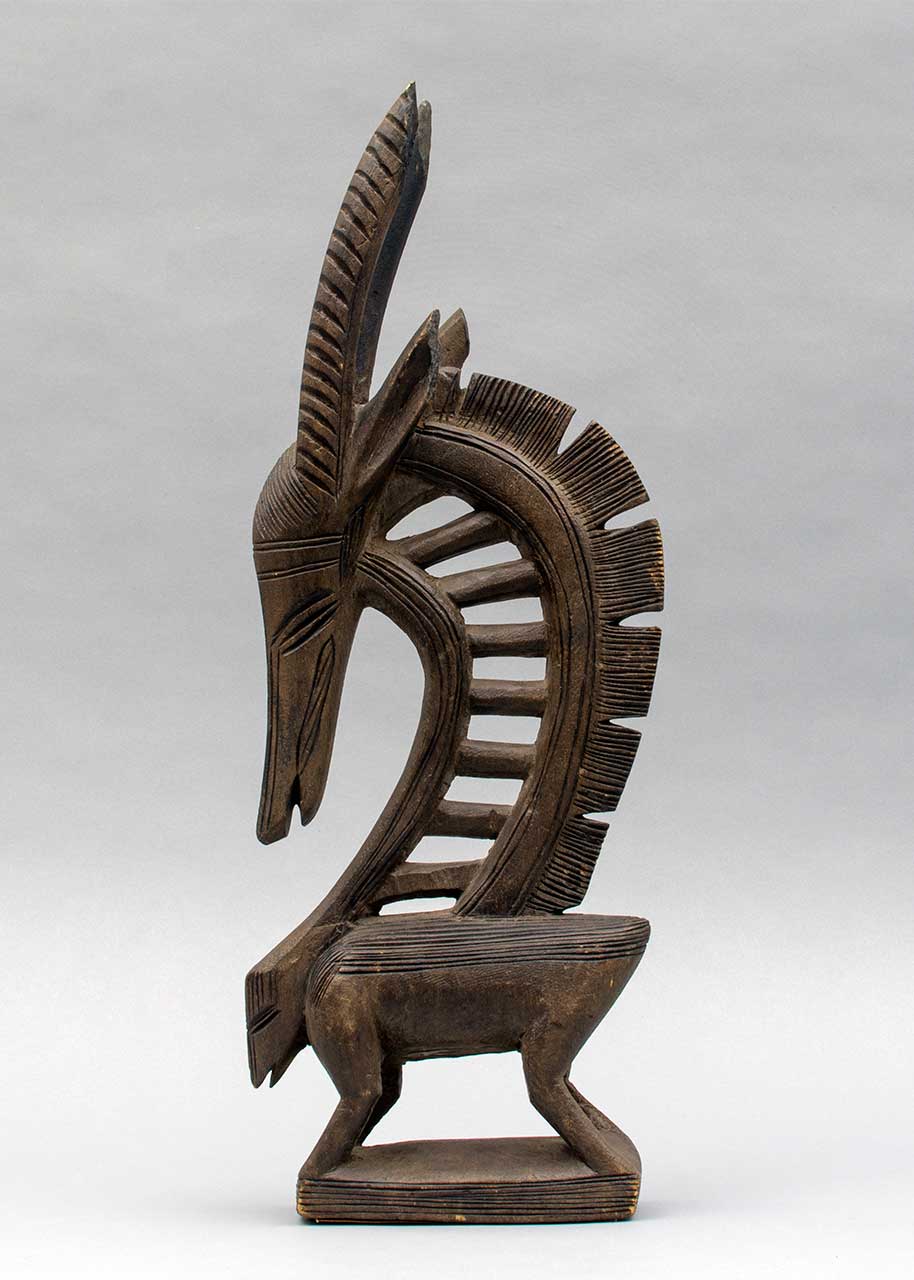 photograph of abstract wooden antelope shaped carving, showing the full side profile
